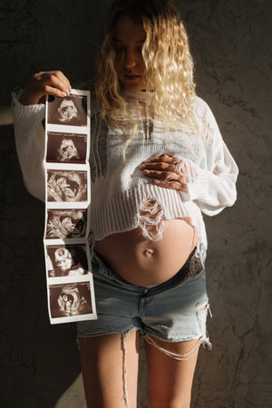 Portrait of a pregnant girl with an ultrasound scan in her hands. beautiful natural lightの写真素材