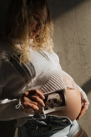 Portrait of a pregnant girl with an ultrasound scan in her hands. beautiful natural lightの写真素材