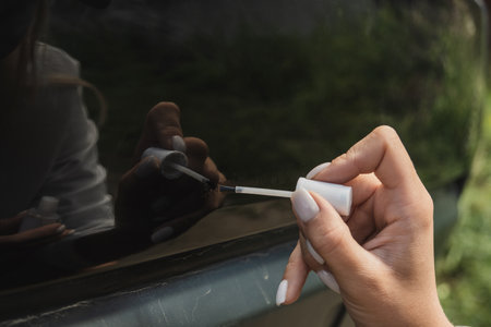 Touching up a body car with a small brush by a young womanの写真素材