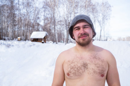 The sweaty man in a hat after sauna outdoors in winter. Steam due to temperature difference. selective focusの写真素材