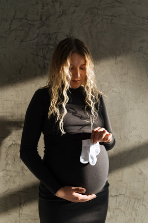 Portrait of a pregnant girl with small socks in her hands. beautiful natural lightの写真素材