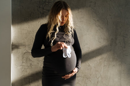 Portrait of a pregnant girl with small socks in her hands. beautiful natural lightの写真素材