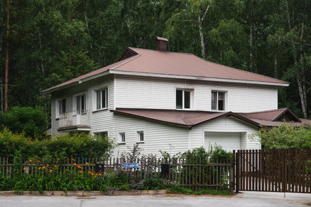 The old private house encased in aluminum siding in the middle of a green forest in summer. outdoors, rural sceneの写真素材