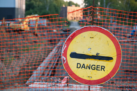 Shabby danger sign on the background of construction site and excavatorの写真素材