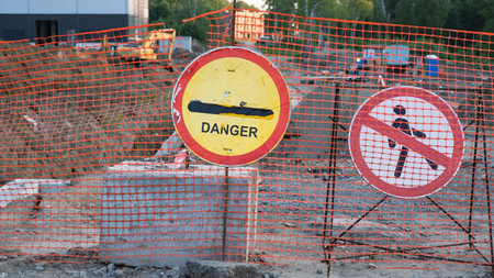 Shabby danger sign on the background of construction site and excavatorの写真素材