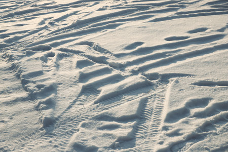Footprints and car tire marks in the snowの写真素材