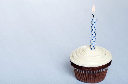 chocolate cupcake with vanilla frosting and a candle