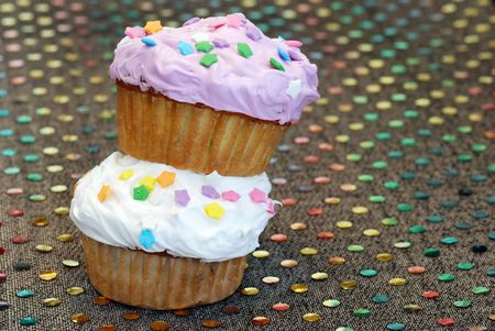 Two cupcakes on a colorful tableclothの写真素材