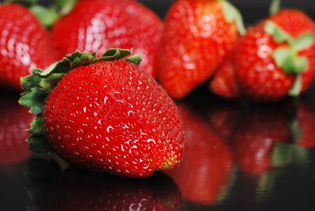 Strawberries on black with reflectionの写真素材