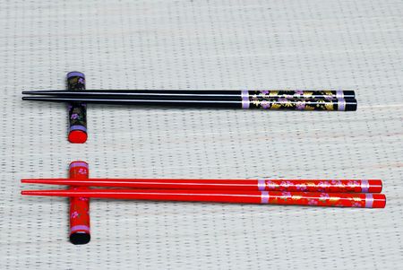 Red and black chopsticks on a bamboo matの写真素材