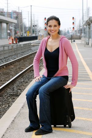 woman sitting on luggage waiting for trainの写真素材