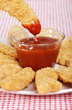 dipping chicken finger in BBQ sauceの写真素材