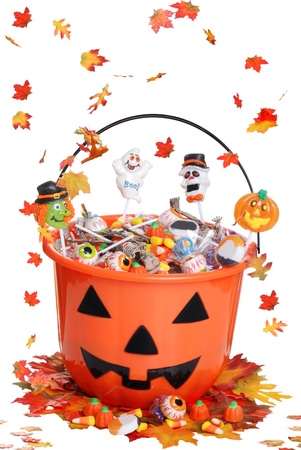 halloween pumpkin bucket with candy and falling  leavesの写真素材