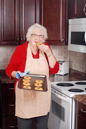 senior woman eating fresh cookieの写真素材