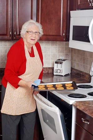 senior woman with tray of fresh baked cookiesの写真素材