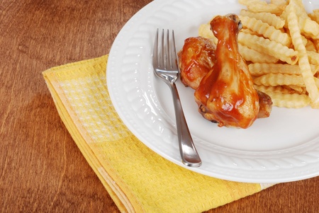barbecue chicken legs with fries and yellow napkinの写真素材