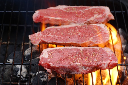 Barbecuing strip loin steaksの写真素材