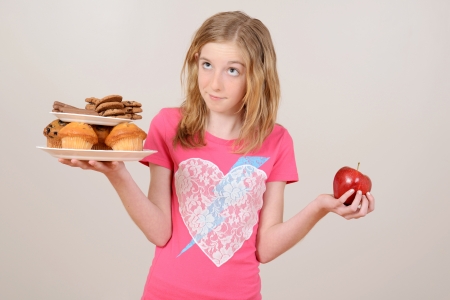 Young girl deciding junk food or appleの写真素材