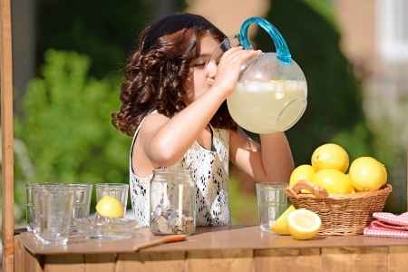 little girl drinking from lemonade pitcherの写真素材