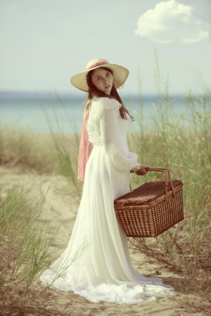 woman at the beach with picnic basketの写真素材