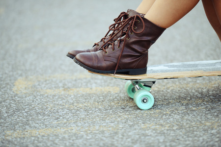 closeup girl with boots sitting on skate boardの写真素材
