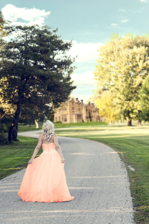 woman in evening dress walking to manor houseの写真素材