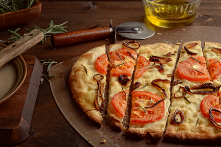 Closeup sliced Focaccia With Caramelized Onions Tomatoes and Fresh Rosemaryの写真素材