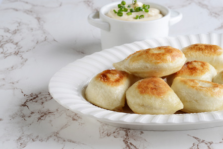closeup pierogies on a platter with sour cream and spring onionsの写真素材