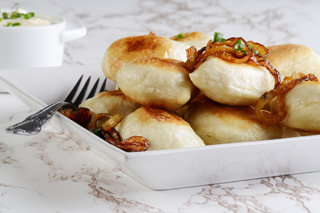 closeup crispy pierogies with spring onions on a plateの写真素材