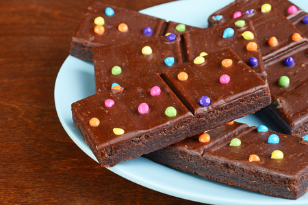 closeup chocolate fudge brownies with candy pieces on blue plateの写真素材