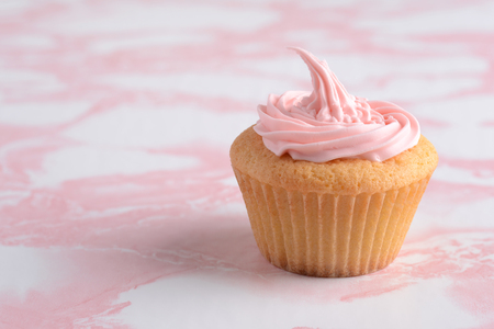 cupcake with pink frosting on marble tableの写真素材
