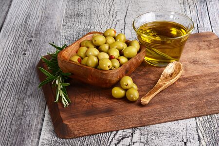 closeup wood bowl of pimento olives with dish of olive oilの写真素材