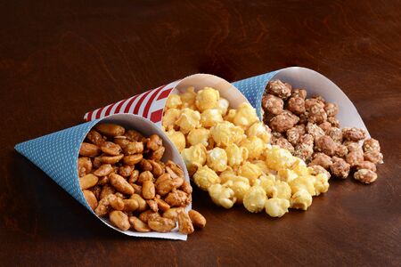 honey peanuts with caramel popcorn and honey sesame seed almonds in paper conesの写真素材
