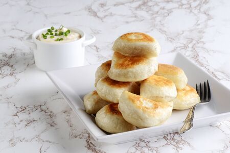 pile of pierogies with sour cream and spring onions and a forkの写真素材