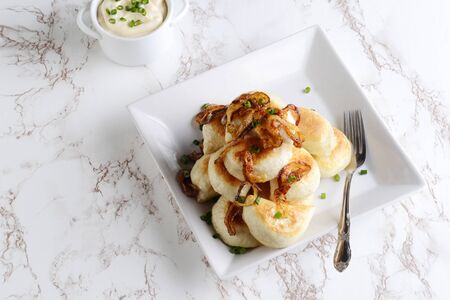 top view pierogies with sour cream caramelized onions and a forkの写真素材