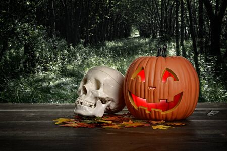 halloween pumpkin and skull in the evening on wood tableの写真素材