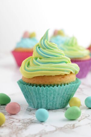 closeup of colorful yellow and blue easter swirl cupcake with mini eggsの写真素材