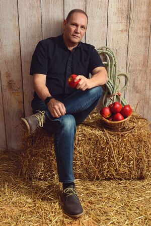 man sitting on hay bale holding an appleの写真素材