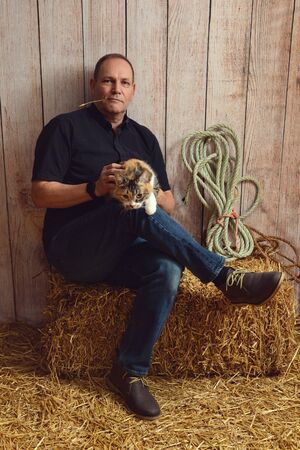 man playing with cat in a barnの写真素材