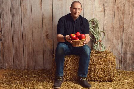 man with basket of red apples in a barnの写真素材