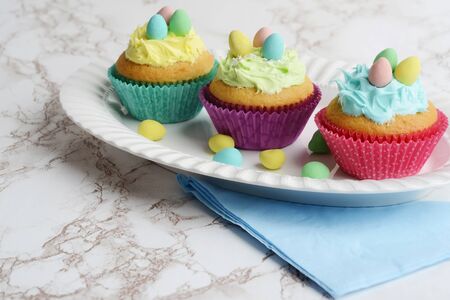 three colorful easter cupcakes with chocolate mini eggsの写真素材