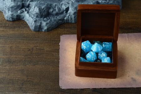 box of blue d & d dice with old paper on tableの写真素材