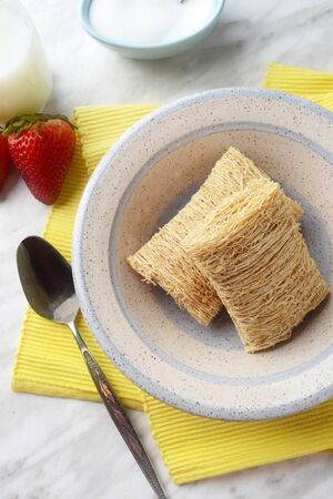 breakfast bowl of shredded wheat with strawberries and yellow napkinの写真素材