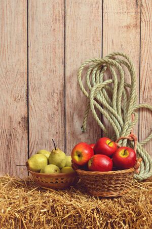closeup apples and pears in basket on hay bale in a barnの写真素材