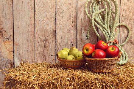 apples and pears in baskets on straw baleの写真素材