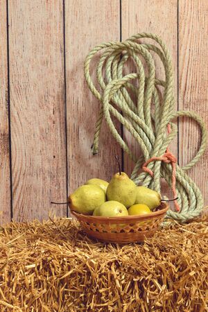 closeup wicker basket of pears on hay baleの写真素材