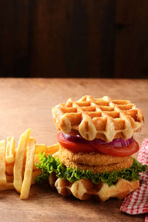chicken burger waffle sandwich with lettuce tomato and french friesの写真素材