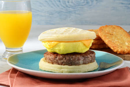 closeup breakfast sausage egg waffles sandwich with orange juiceの写真素材