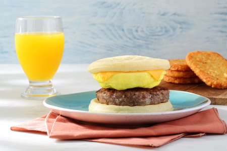 sausage egg cheese waffles sandwich with glass of orange juiceの写真素材
