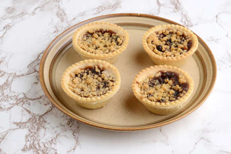 four fruit crumble tarts on a brown plateの写真素材